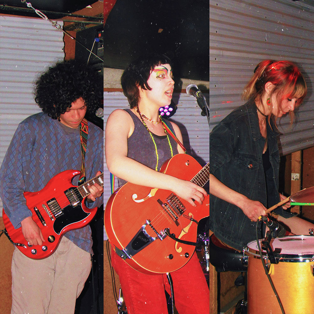 Three musicians playing guitar and drums in a casual setting.