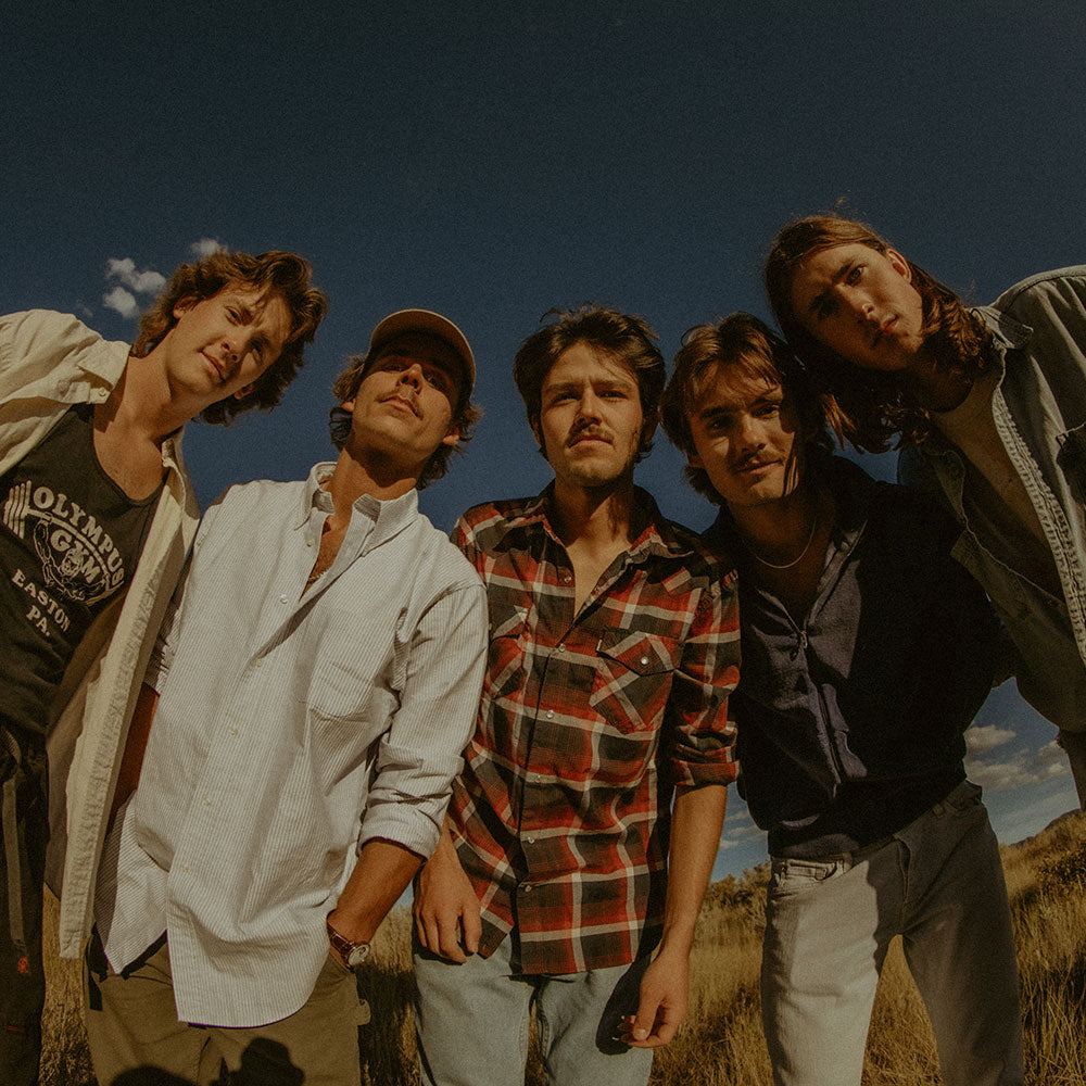 Five people standing together outdoors with a clear sky